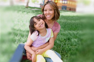 Mother and daughter sitting together in park setting