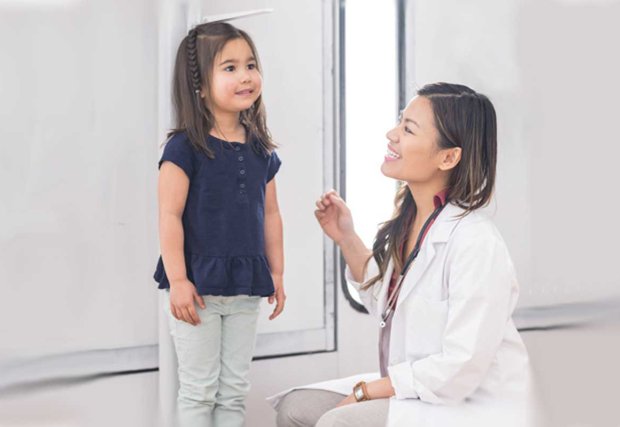 Doctor midiendo la altura del niño pequeño